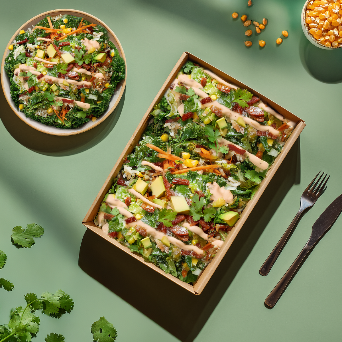 Salad in a wooden box with a bowl on a green background