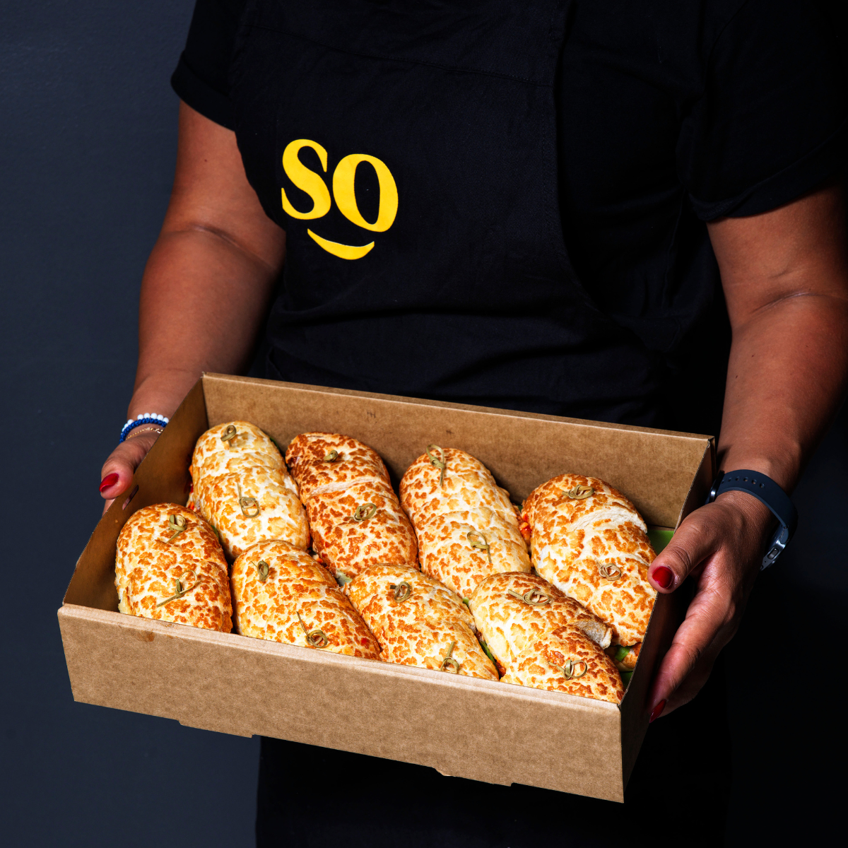 Person holding a box of corn on the cob with a dark background